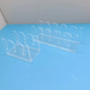 Clear acrylic hat storage rack with multiple hooks displayed on a blue surface.