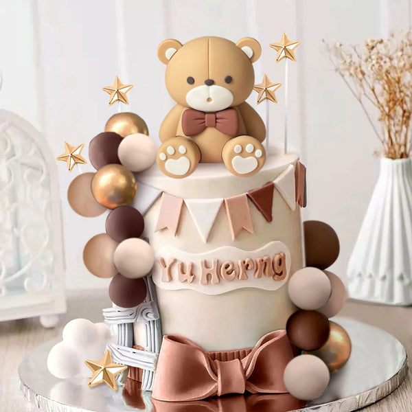 A round cake decorated with a bear figure and brown and gold decorative balls.