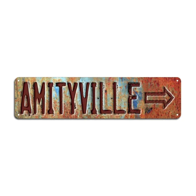 A rustic, weathered metal sign with the text AMITYVILLE and an arrow pointing to the right.