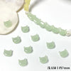 A string of light green cat head glass beads for jewelry making, with a white bead visible in the background.
