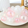 A cluster of clear and pink iridescent balloons used as cake toppers for party desserts.