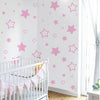 Pink star vinyl wall decal featuring various sized stars on a white wall with a crib in the foreground