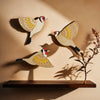 Three vintage wooden bird wall decorations with natural wood tones and painted details cast shadows on a beige wall.