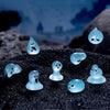 A set of eight glow-in-the-dark resin fairy water droplet figurines resting on a dark, textured surface.