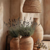 A collection of terracotta vases and dried lavender sprigs displayed on a light wooden surface.