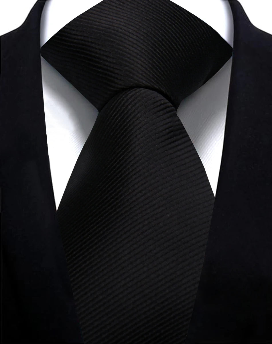 A close-up shot of a black silk necktie tied in a simple knot against a black suit jacket.