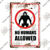 A vintage warning metal sign with a red border and black silhouette of a skull, reading NO HUMANS ALLOWED.