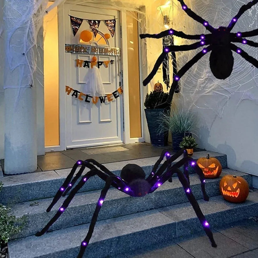 A large black LED light-up spider decoration with purple glow is displayed on a doorstep near a white door.