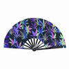 A folding rave hand fan featuring a dark background with vibrant purple and green fluorescent cannabis leaf patterns.