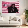 Eine Person in einem dunklen Hoodie hält aggressiv eine weiße Gabel vor einer rosa-weißen amerikanischen Flaggen-Tapisserie.