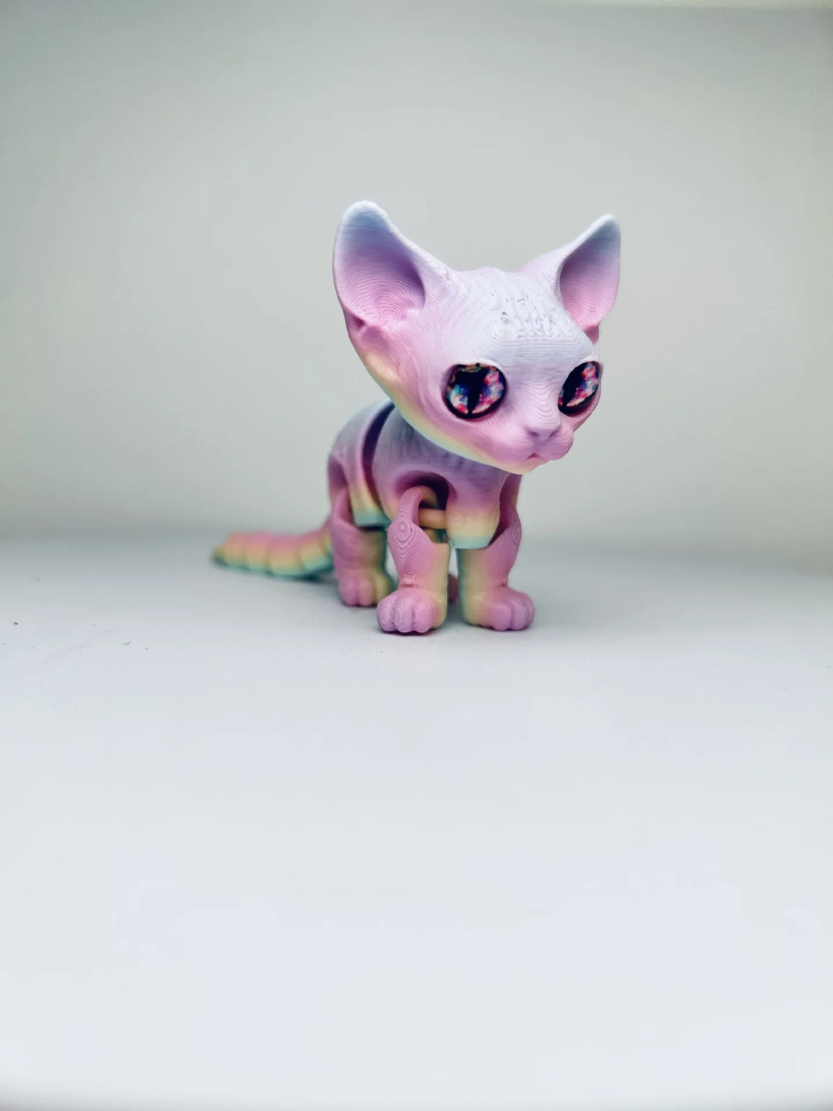 A small, articulated 3D printed figurine of a Siamese cat with purple and pink coloration.