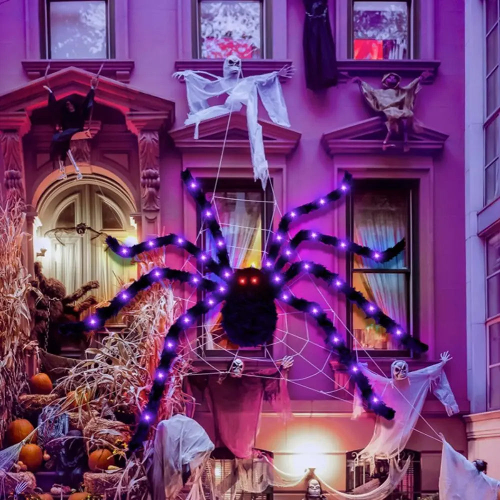 A large spider web made of purple LED lights is displayed in front of a pink building facade.