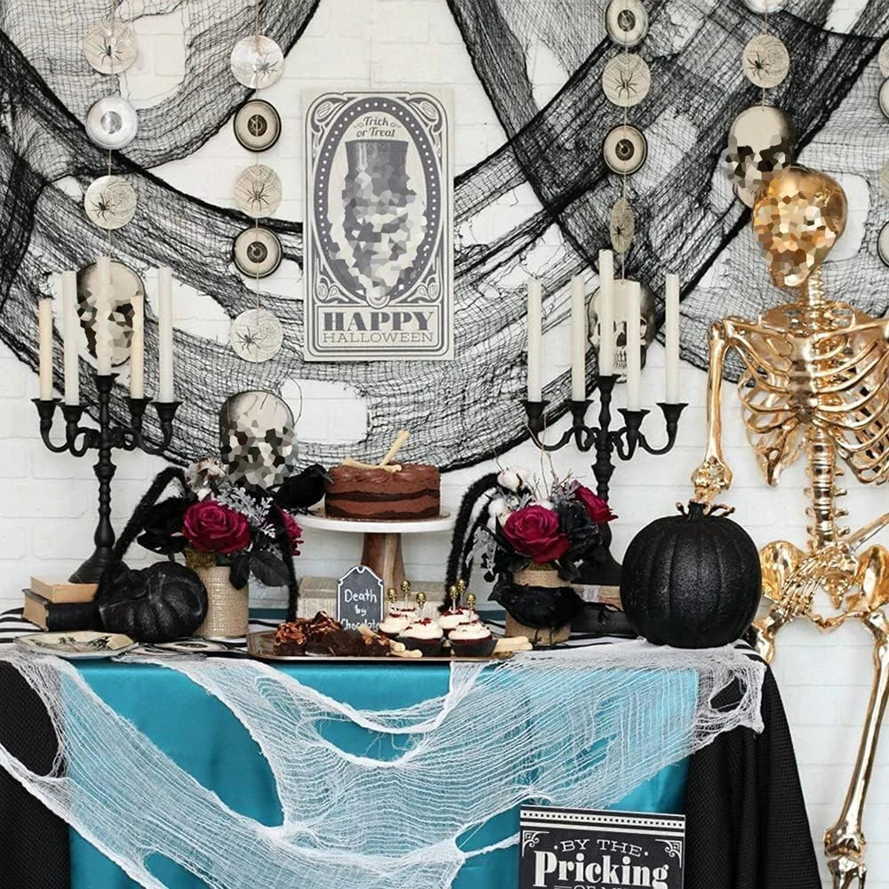 A spooky Halloween decoration display featuring a table covered with blue fabric and black gauze fabric decorations.