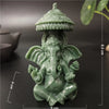 A small, green bronze statue of Ganesha Buddha seated in a meditative pose with a tiered crown.