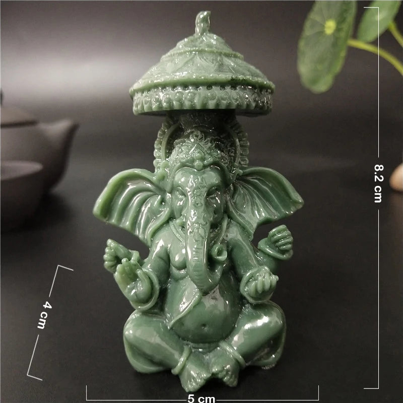 A small, green bronze statue of Ganesha Buddha seated in a meditative pose with a tiered crown.