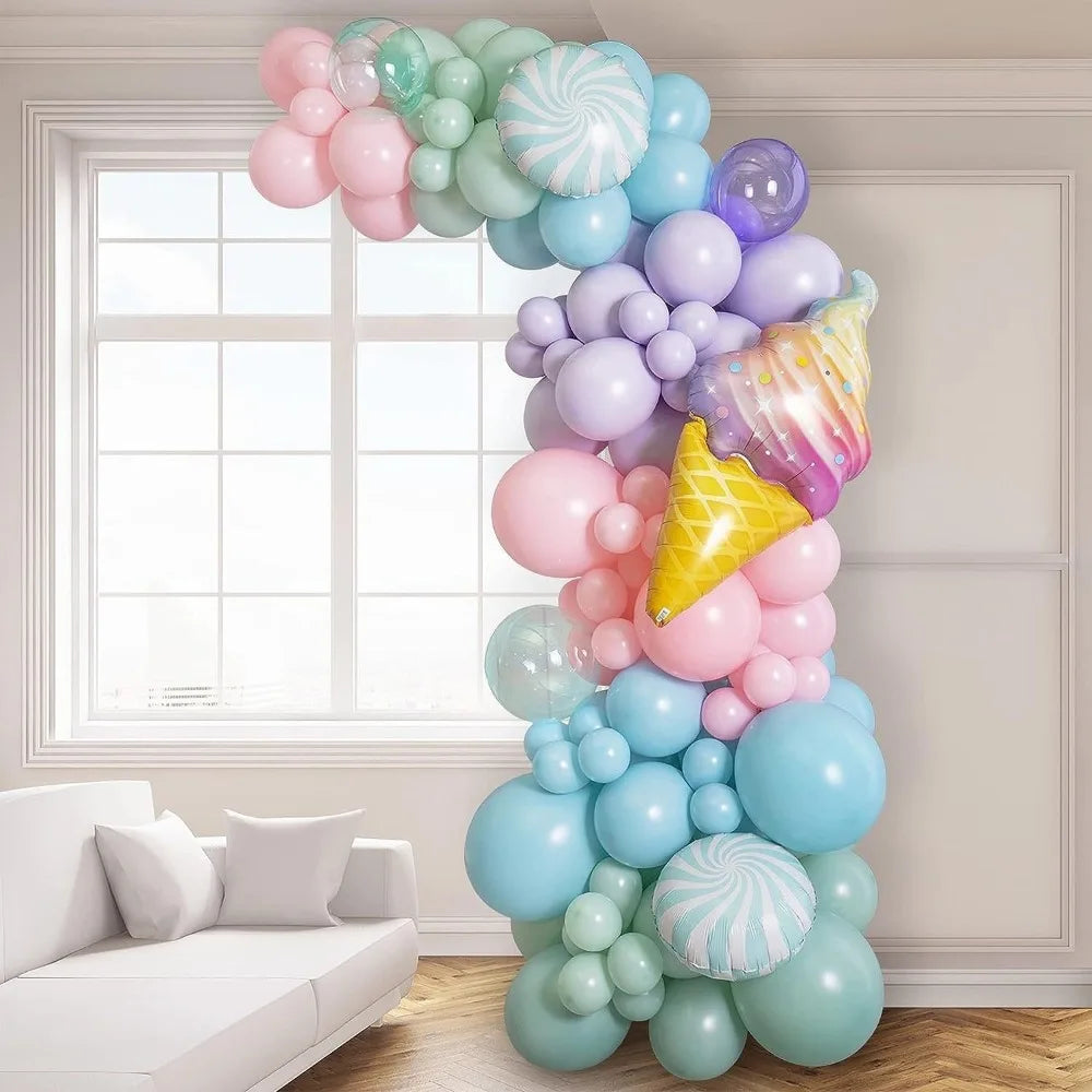 A colorful balloon arch kit featuring pastel pink, blue, and purple balloons displayed indoors near a window.