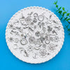 A collection of vintage ship anchor charms and nautical jewelry components displayed on a white scalloped plate.