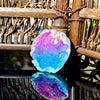 Iridescent blue and pink agate crystal geode stone resting on a dark surface.