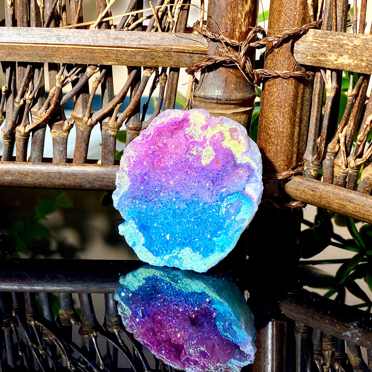 Iridescent blue and pink agate crystal geode stone resting on a dark surface.