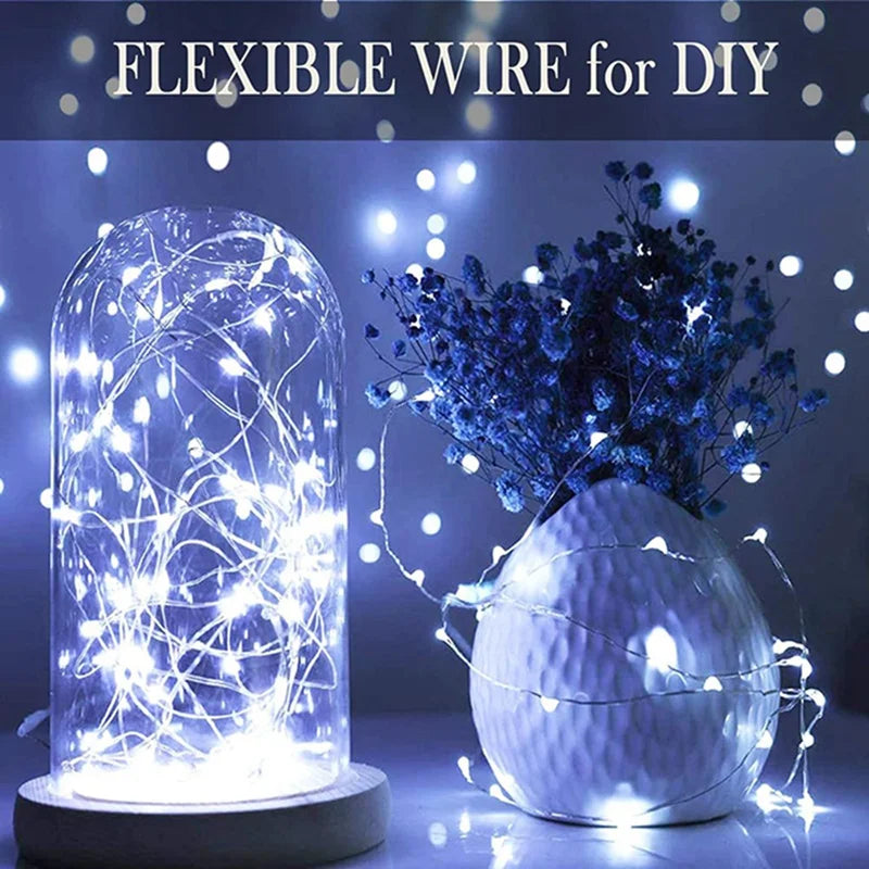 A clear glass orb filled with bright white fairy lights, displayed next to a white textured sphere.