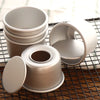A stack of five round, light-colored non-stick cake molds with removable bases resting on a wire rack.