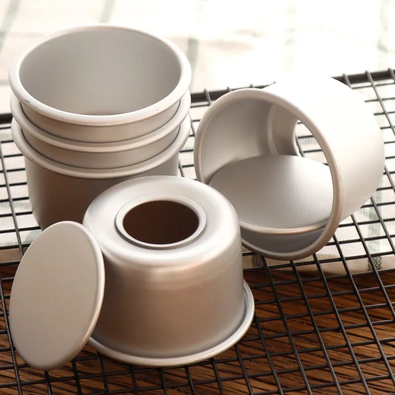 A stack of five round, light-colored non-stick cake molds with removable bases resting on a wire rack.
