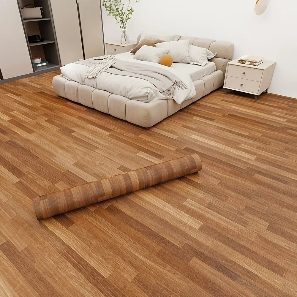 A close-up view of realistic wood grain floor stickers installed on a light brown wooden floor.