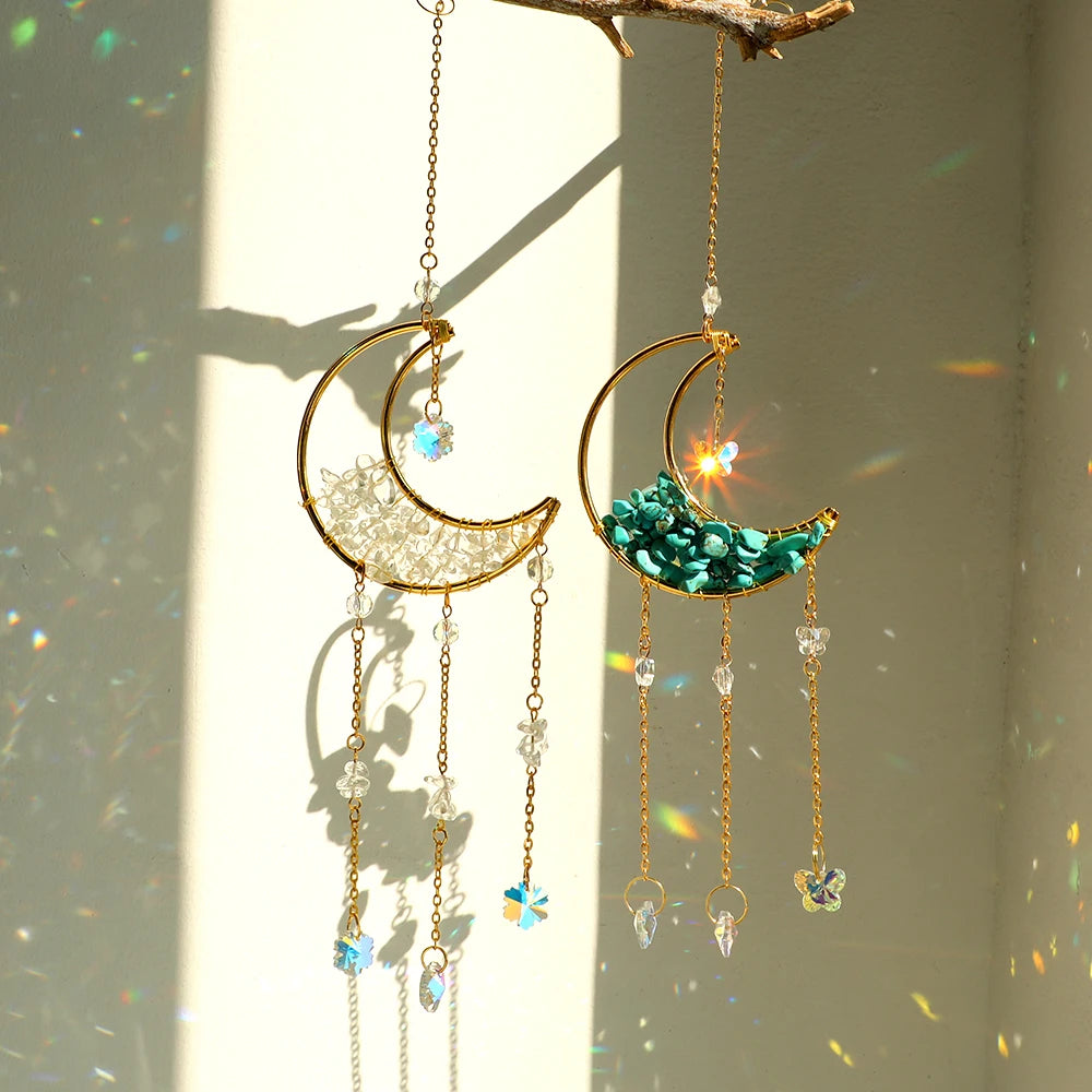 Gold moon-shaped crystal suncatcher with iridescent teal and blue crystals hanging from a branch.