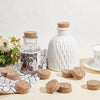 White ceramic bottle and several cork circles displayed on a light surface.