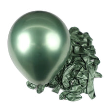 A single shiny metallic green latex balloon resting on a pile of crumpled green foil balloons.