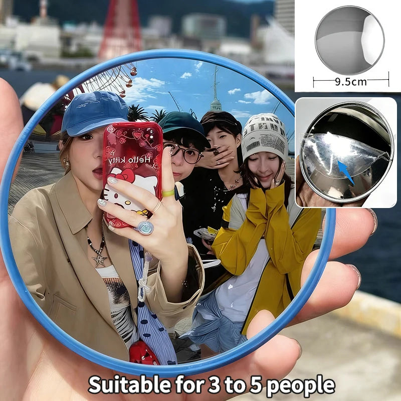 A round convex mirror is held up by a person, showing a reflection of a group of people.