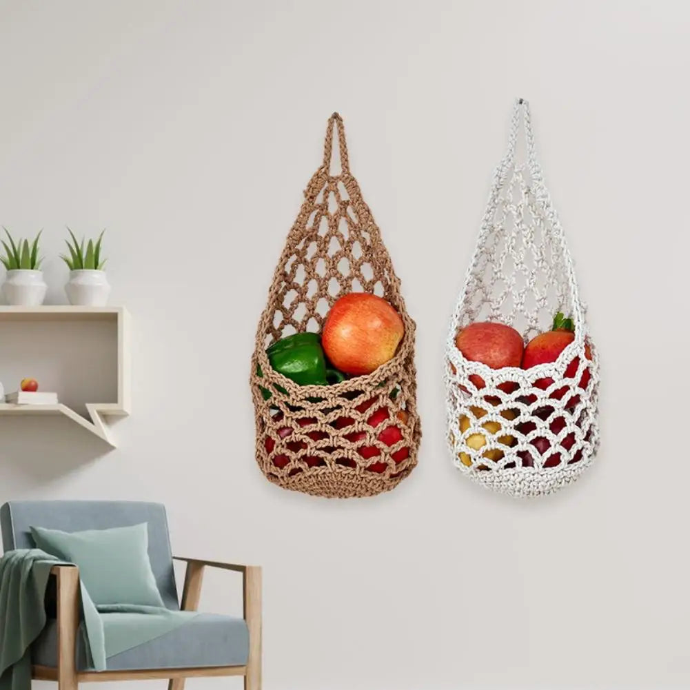 Two macrame hanging storage baskets, one brown and one white, filled with fresh produce.