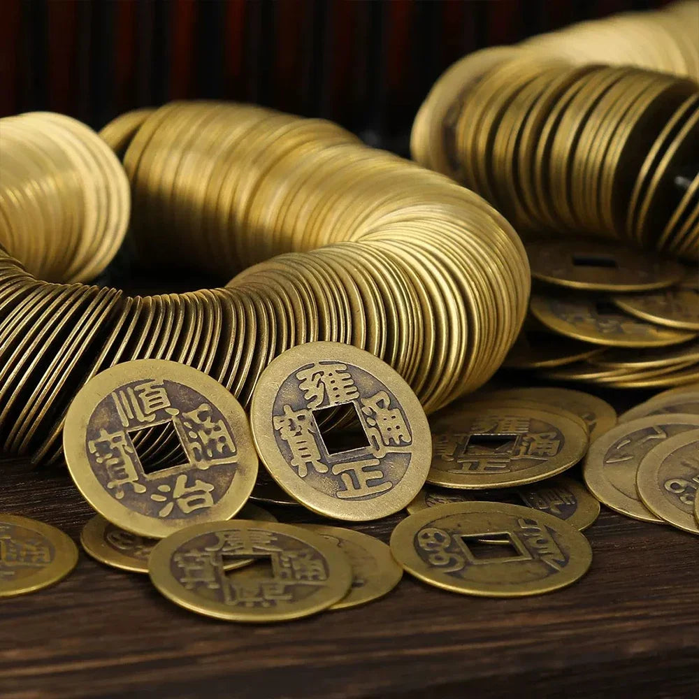 A pile of antique gold Chinese Feng Shui coins for wealth and good fortune resting on a dark wooden surface.