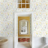 A room featuring boho floral peel and stick wallpaper on the walls, with a white framed doorway leading to another area.
