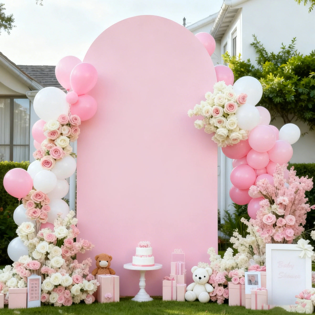 A pink wedding arch cover decorated with pink and white balloons and floral arrangements.