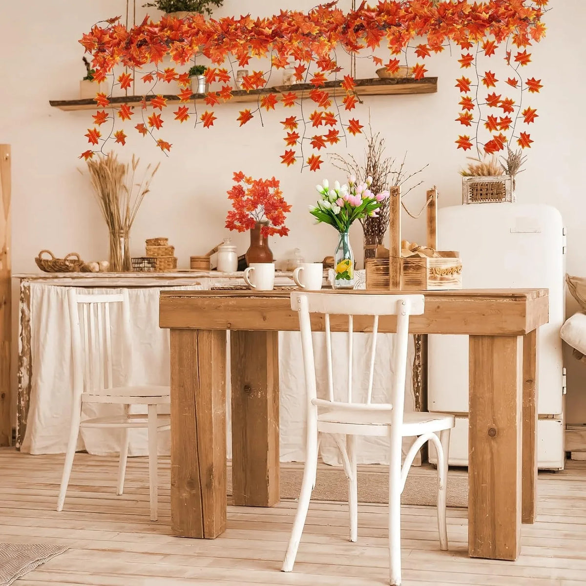 A rustic wooden table set with white chairs and an orange maple leaf garland hanging above.