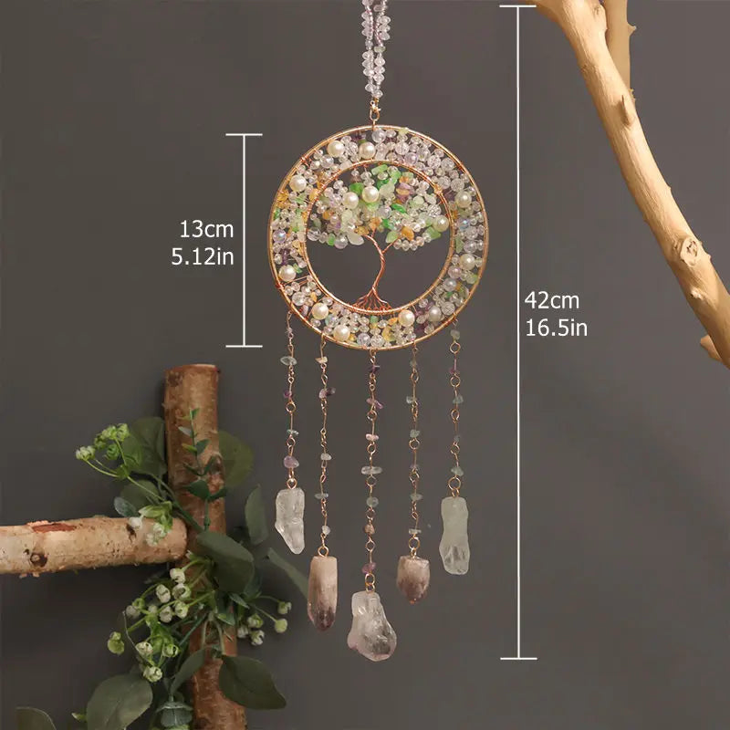 A hanging crystal tree of life sun catcher featuring a circular gold frame and dangling quartz crystals.