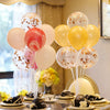 A display of assorted white, pink, and yellow balloons arranged in a column stand for events.