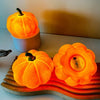 An orange decorative LED pumpkin night light sits on a wooden surface.