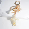 Gold-toned keychain featuring a cross and a butterfly charm made of clear resin