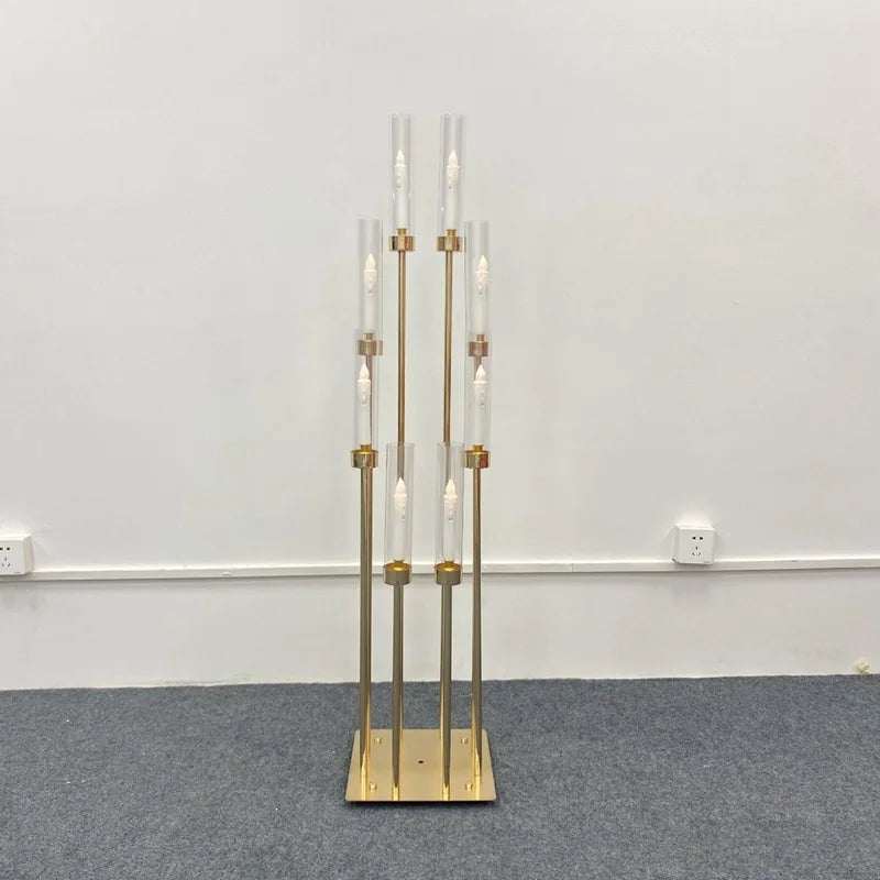 A tall gold metal candelabra set featuring eight glass candle holders displayed against a white wall.