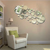 A beige armchair sits in a room with a wall decorated by a cluster of round mirrors.