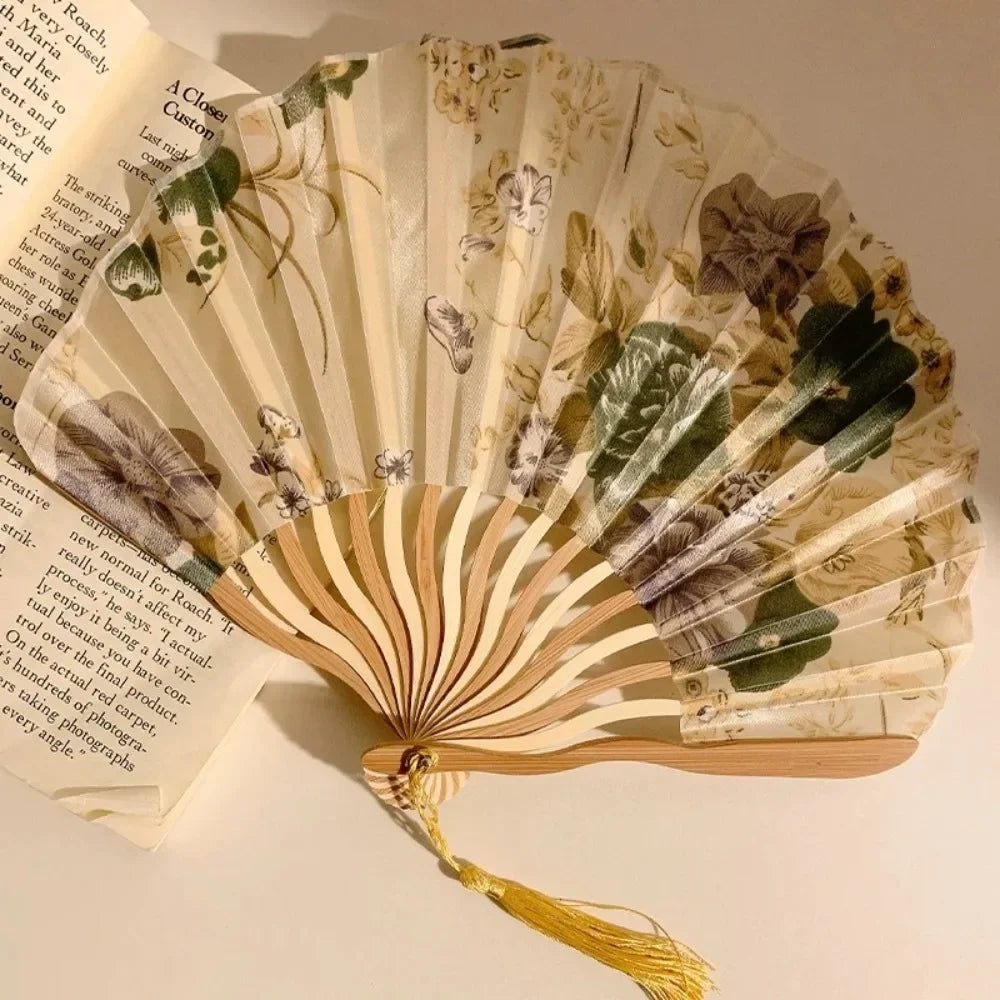A folding hand fan with leopard print and a black handle, featuring natural tones and floral patterns.