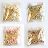 A collection of pearl-tipped bamboo cocktail picks in white and rose gold finishes packaged in clear plastic.