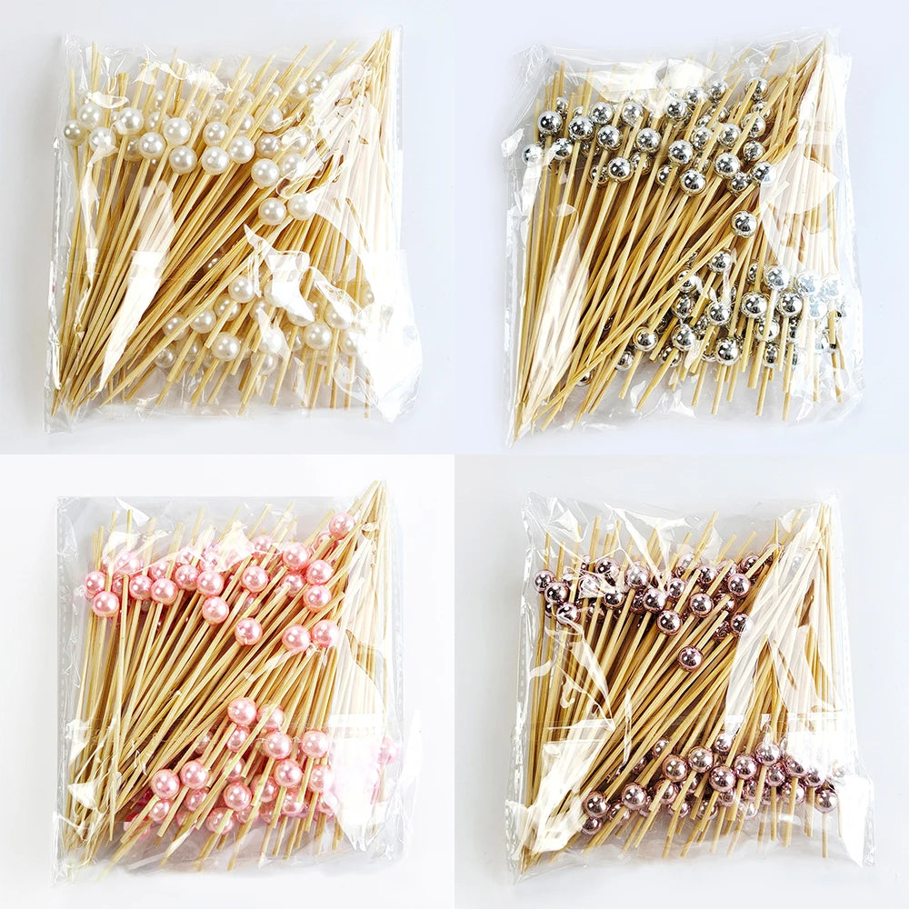 A collection of pearl-tipped bamboo cocktail picks in white and rose gold finishes packaged in clear plastic.