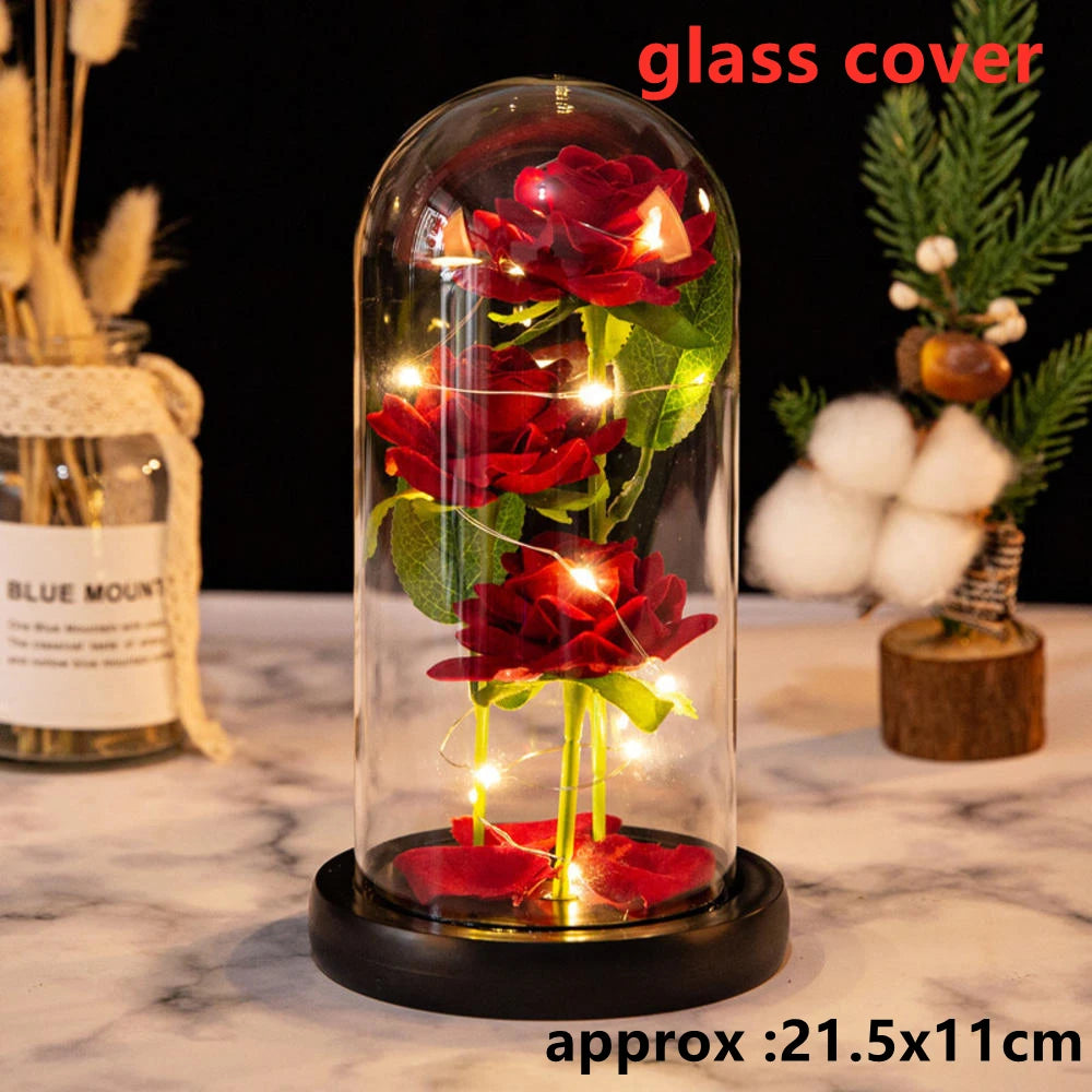 A glass dome containing a red rose artificial flower illuminated by LED lights on a black base.
