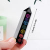 A black obsidian crystal tower with seven colored crystals is shown being held, demonstrating its size.