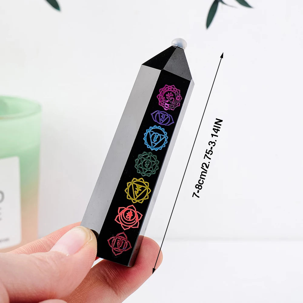 A black obsidian crystal tower with seven colored crystals is shown being held, demonstrating its size.
