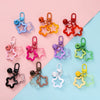 A collection of colorful star charm pendant keychains arranged on a pink and blue background.