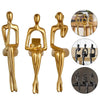 A set of three abstract thinker sculptures in gold and black resin for modern desk decor.